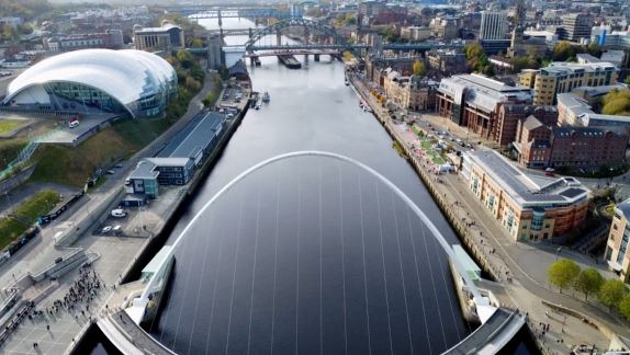 erial shot of a modern arched bridge spanning over a river in a cityscape